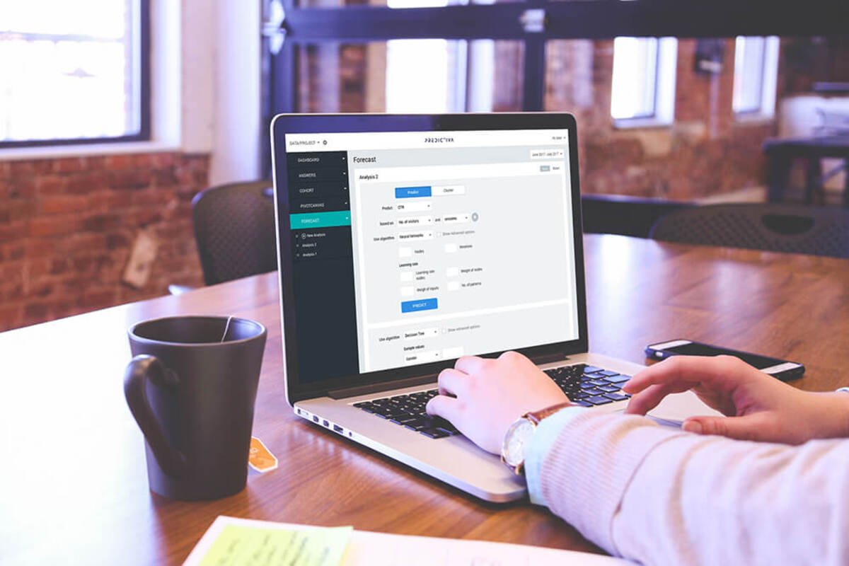 Realistic mockup of person using Predictiva on laptop in the café